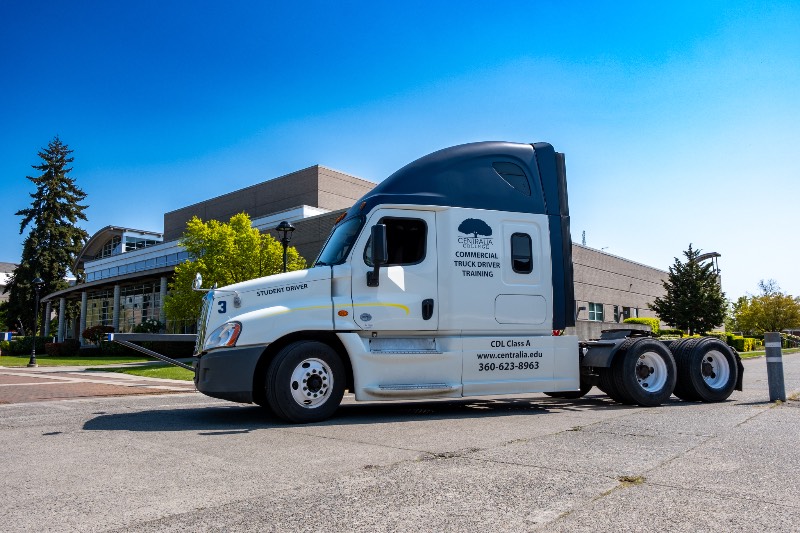 A photo of the Centralia College CDL truck parked next to the TransAlta Commons building on a beautiful, sunny day.