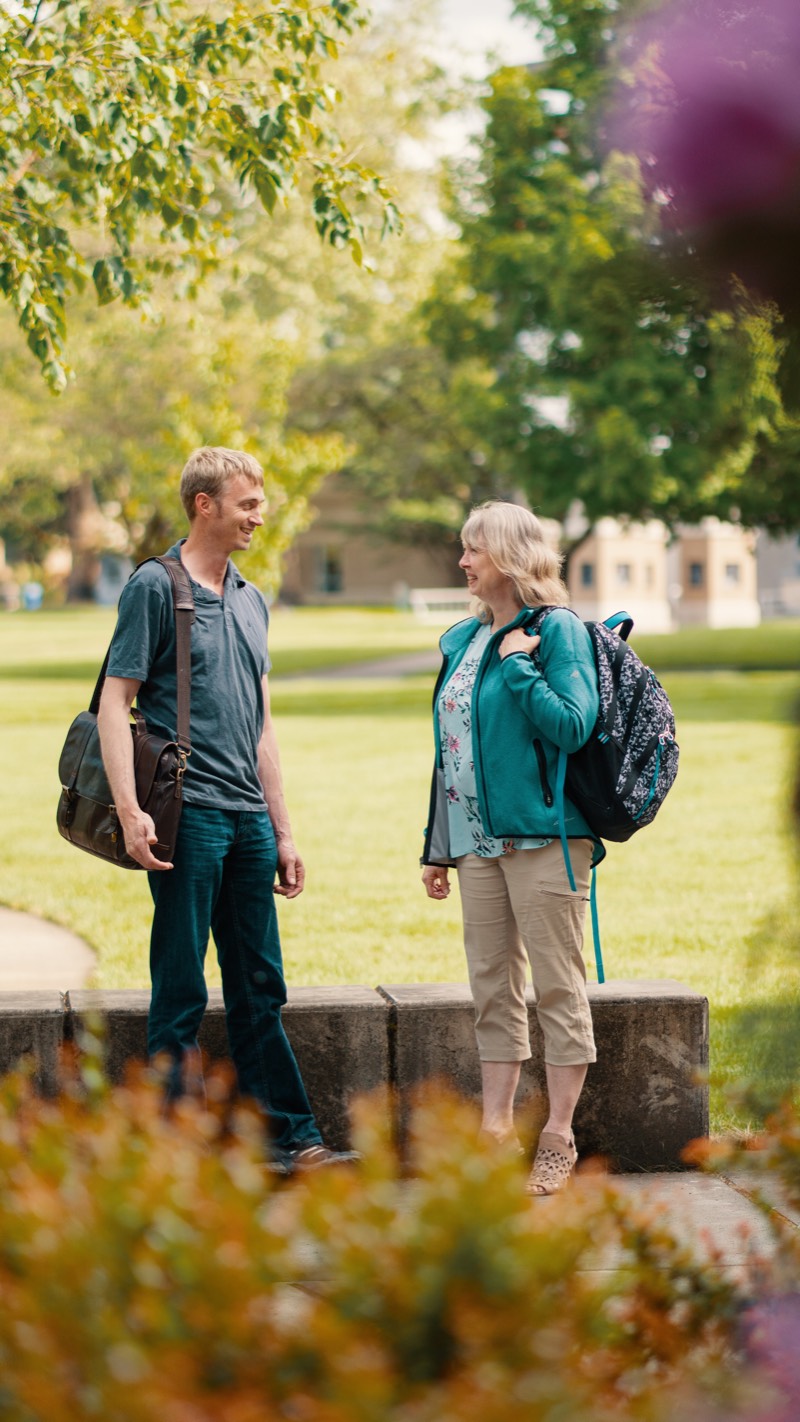 Two bachelor's degree students talk on the esplanade outside