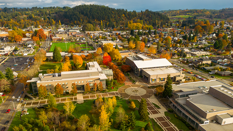 An aerial photo of the Centralia College campus in the fall with bright red and orange leaves, a stunning blue sky, and the lush green trees and grass of campus