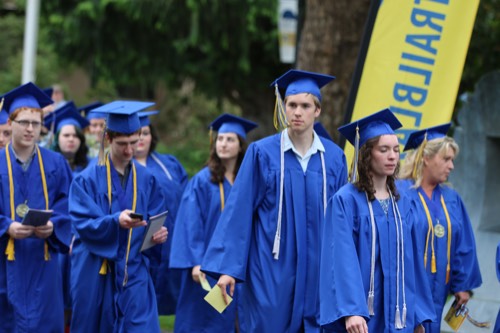 A photo of Centralia College students walking in their blue caps and gowns into the commencement ceremony