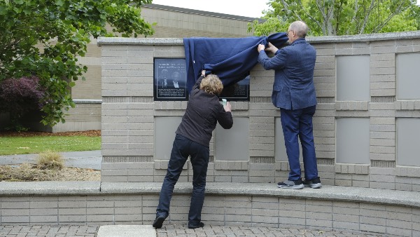 College employees take the cover off the Rikkey Outumoro plaque at the dedication ceremony